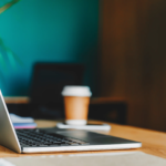 Ordinateur sur un bureau avec un café dans le fond