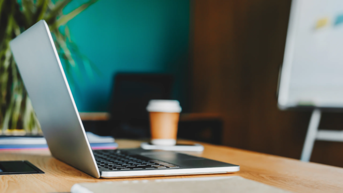 Ordinateur sur un bureau avec un café dans le fond